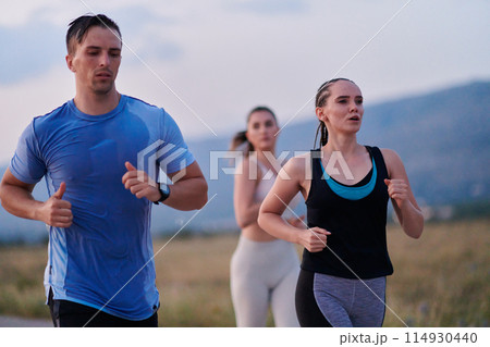 A diverse group of runners trains together at sunset. 114930440