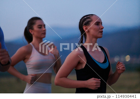 A diverse group of runners trains together at sunset. A diverse group of runners trains together at sunset. 114930441