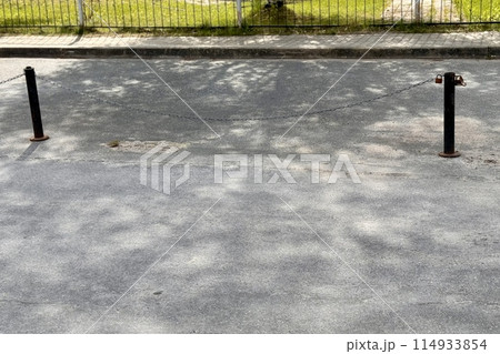 Metal restraints with an iron chain with a key for parking a car between poles outdoors in a special area on a summer day Metal restraints with an iron chain with a key for parking a car between poles outdoors in a special area on a summer day 114933854