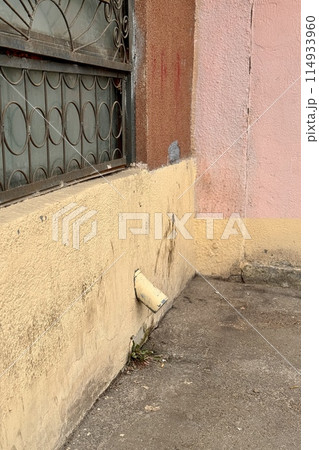 Yellow stainless steel drain pipe for drain pipe with water drainage from roof the house to the ground. It attaches to a wall of residential building 114933960