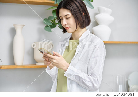 部屋でスマホを見る若い女性 114934981