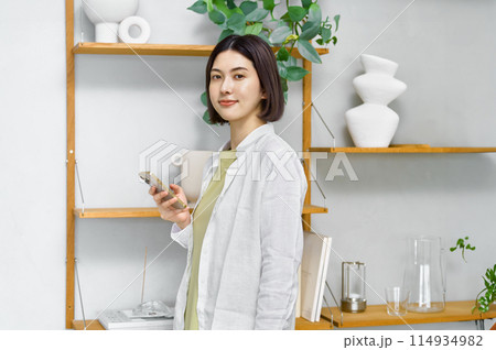 部屋でスマホを見る若い女性 114934982