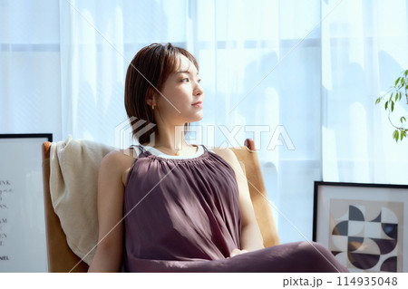 部屋の中で椅子に座って朝日を浴びてくつろぐ 114935048