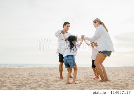 Pure happiness captured on beach as an Asian family father and mother holding children jump into air. beautiful ocean background adds touch of serenity to this lively portrayal of family fun. 114937117
