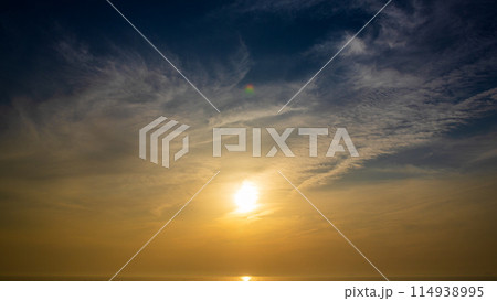 夕暮れの空に沈む夕陽と流れゆく雲 夕暮れの空に沈む夕陽と流れゆく雲 114938995