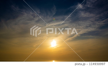 夕暮れの空に沈む夕陽と流れゆく雲 夕暮れの空に沈む夕陽と流れゆく雲 114938997