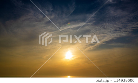 夕暮れの空に沈む夕陽と流れゆく雲 114939000