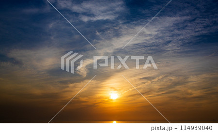 夕暮れの空に沈む夕陽と流れゆく雲 114939040