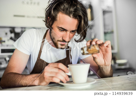 Handsome barista working in coffee shop, preparing coffee. University student working part-time in cafe. Handsome barista working in coffee shop, preparing coffee. University student working part-time in cafe. 114939639