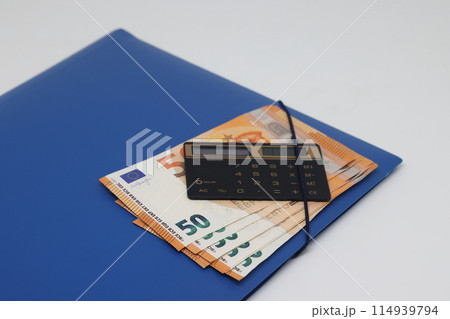 Calculator and banknotes lie on a folder for papers, financial accounting and control. 114939794