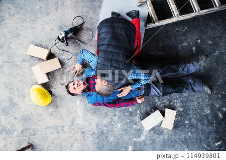 Colleague performing CPR on an injured worker lying on the ground after accident. Concept of occupational safety and health in workplace. 114939801