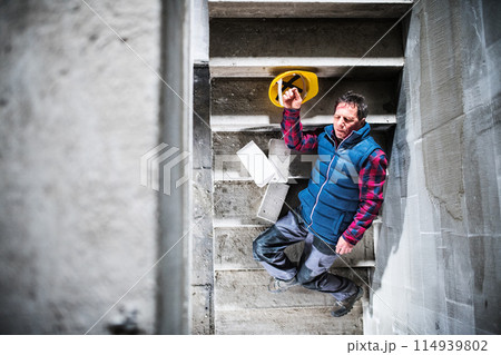 Male worker lying on the stairs after fall. Work injury, accident in workplace. Male worker lying on the stairs after fall. Work injury, accident in workplace. 114939802