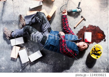 An unconscious man worker lying on the floor after a head injury. Work injury, accident in workplace. 114939821