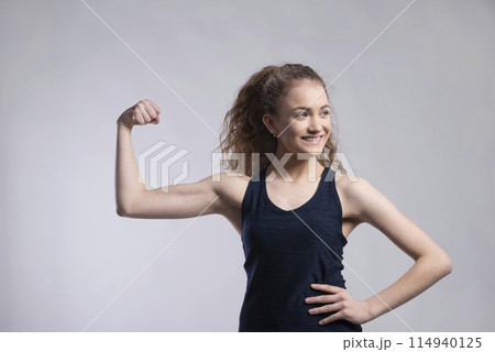Portrait of a gorgeous fitness girl with curly hair, flexing muscles. Studio shot, white background with copy space Portrait of a gorgeous fitness girl with curly hair, flexing muscles. Studio shot, white background with copy space 114940125