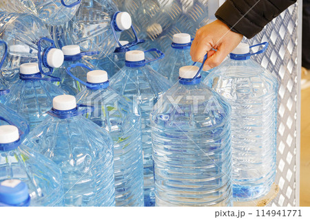 A person is extending their hand to grab a bottle of refreshing water 114941771