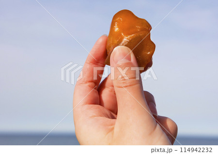 Amber. Bright and transparent amber against a bright blue sky. Solidified wood resin. 114942232