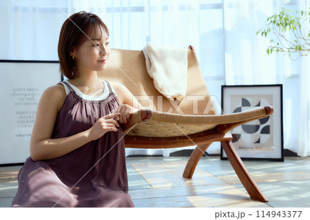 部屋の中で椅子にもたれてくつろぐ女性 114943377