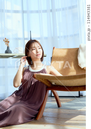 部屋の中で椅子にもたれてくつろぐ女性 114943381