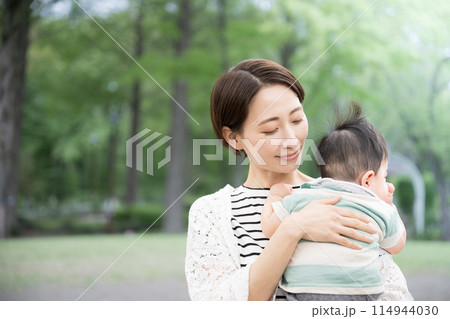 新緑の公園で赤ちゃんを抱く母親 幸せや幸福、見守り守る母性のイメージ 新緑の公園で赤ちゃんを抱く母親 幸せや幸福、見守り守る母性のイメージ 114944030