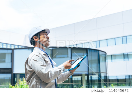 タブレットを使ってビルを点検するエンジニア タブレットを使ってビルを点検するエンジニア 114945672