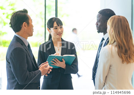 ロビーで通訳を介して会話する多国籍ビジネスパーソンのグループ 114945696