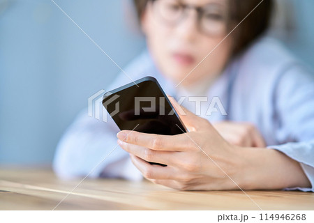 疲れた様子でスマートフォンを操作する女性 114946268