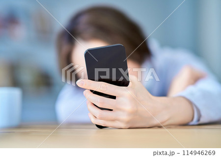 疲れた様子でスマートフォンを操作する女性 114946269