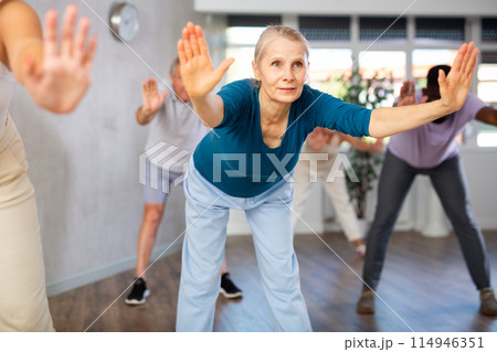 Mature men and women practicing Rock 'n' Roll dance in training hall 114946351