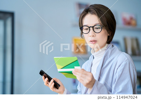 困った表情で銀行口座の通帳を見る女性 困った表情で銀行口座の通帳を見る女性 114947024