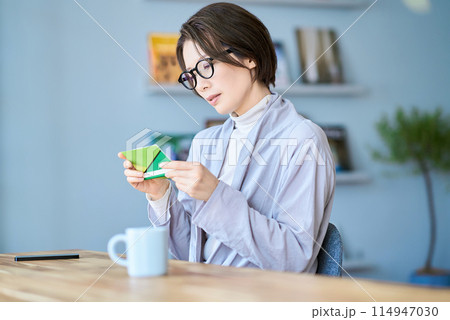 困った表情で銀行口座の通帳を見る女性 114947030