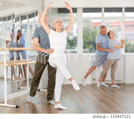 Mature woman practicing ballet positions in pair with man in dance studio Mature woman practicing ballet positions in pair with man in dance studio 114947121