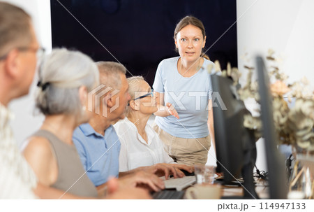 Woman teacher teaching elderly people how to use computer 114947133