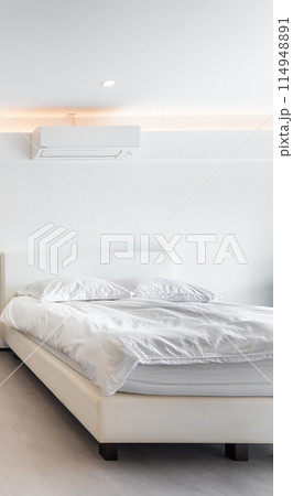 Air conditioner and bed in a white minimal style room. Air conditioner and bed in a white minimal style room. 114948891