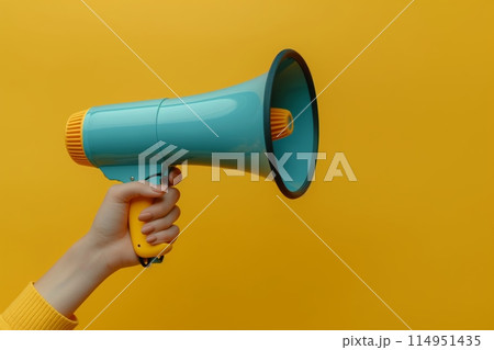 Hand holding a blue megaphone on yellow 114951435