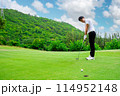 Golfer is using a putter to put a golf ball on the green. 114952148