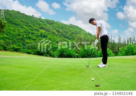 Golfer is using a putter to put a golf ball on the green. 114952148