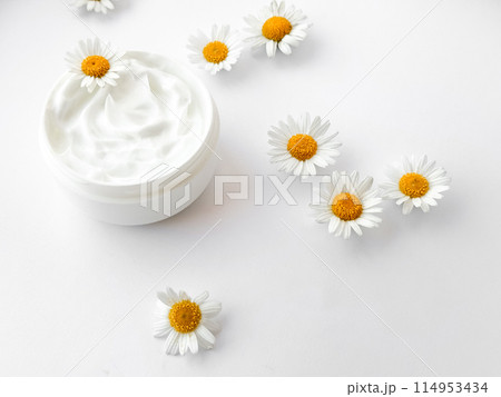 Open jar of white hand or body cream with chamomile flowers on white background. Flat lay composition. For skincare and beauty product concept. 114953434
