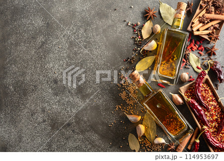 Bottles of olive oil and various spices on a kitchen table. Bottles of olive oil and various spices on a kitchen table. 114953697