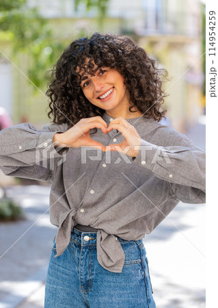 Young woman makes symbol of love, showing heart sign to camera, express romantic positive feelings 114954259