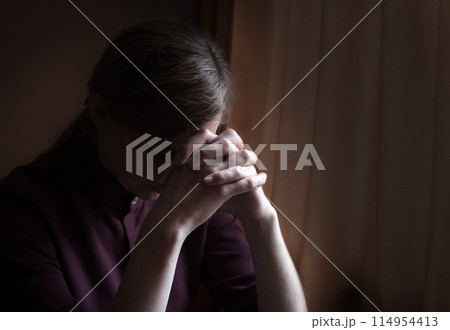 Praying woman at the window 114954413
