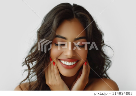 Indian young woman with dark hair, eyes closed, gently holding her face 114954893