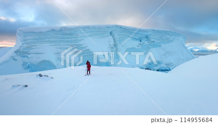 Two men ski on Antarctica snow hill glacier in sunset. Travel, active lifestyle, sport, recreation in Arctic wild nature landscape. Snow covered mountains, icy ocean, winter scene. Aerial drone flight Two men ski on Antarctica snow hill glacier in sunset. Travel, active lifestyle, sport, recreation in Arctic wild nature landscape. Snow covered mountains, icy ocean, winter scene. Aerial drone flight 114955684