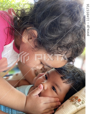 Older sister kissing younger sister lying on the bed Older sister kissing younger sister lying on the bed 114955716