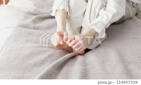 冷えた足を擦る女性 114957339