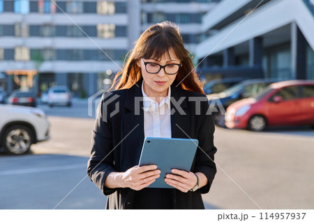 Mature woman manager agent using digital tablet for work, city background 114957937