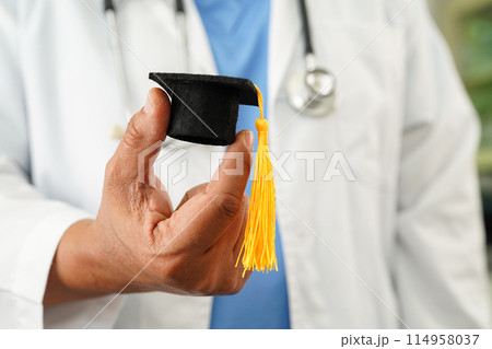 Asian doctor holding graduation gap hat, education medicine. 114958037
