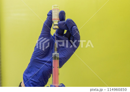 A nurse in blue gloves draws medicine into a syringe for an injection. Treatment in hospital. The doctor prepares a syringe for an injection. Therapeutic injections. A nurse in blue gloves draws medicine into a syringe for an injection. Treatment in hospital. The doctor prepares a syringe for an injection. Therapeutic injections. 114960850