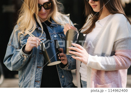 Female friends buy asian food. Girls open boxes and use food sticks. Takeaway food concept 114962400