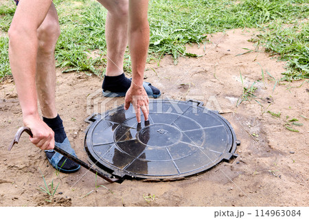 Polymer manhole cover is lifted with pry bar. Polymer manhole cover is lifted with pry bar. 114963084