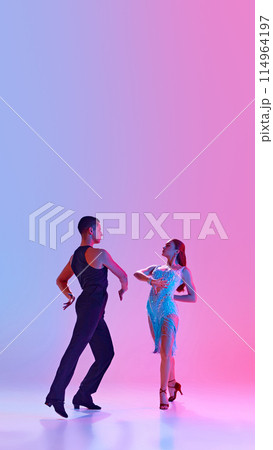 Poster. Young man and woman, ballroom dancers in stage costumes dancing tango energetically in neon lighting against gradient background. 114964197